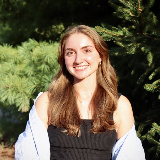 A portrait of Anjali Turchiano, a person with long brown hair and a black shirt.