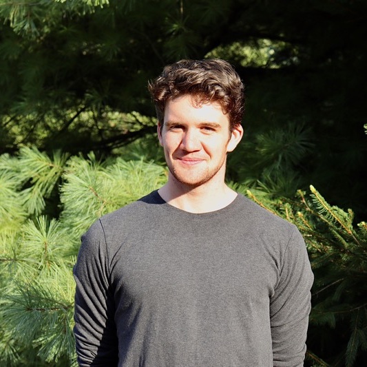 A portrait of Asa Kittay, a person with short brown hair and a dark gray shirt.