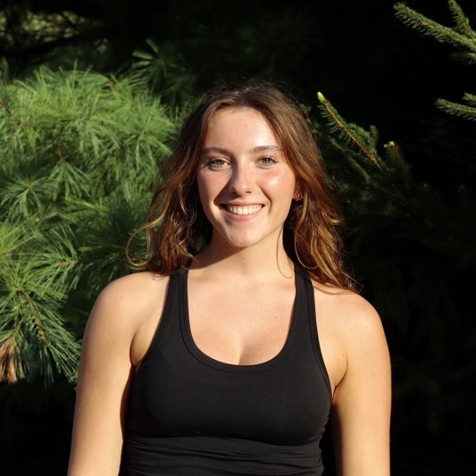 A portrait of Haley Dexter, a person with long brown hair and a black tank top.