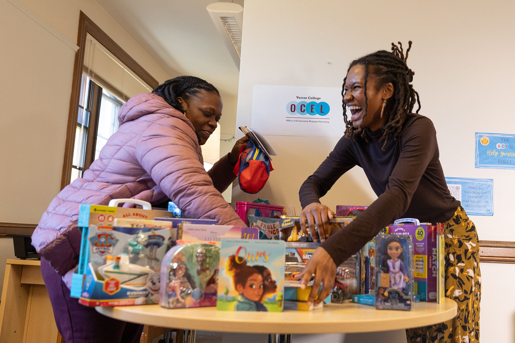 Two people leaning over a table full of gifts while organizing them.