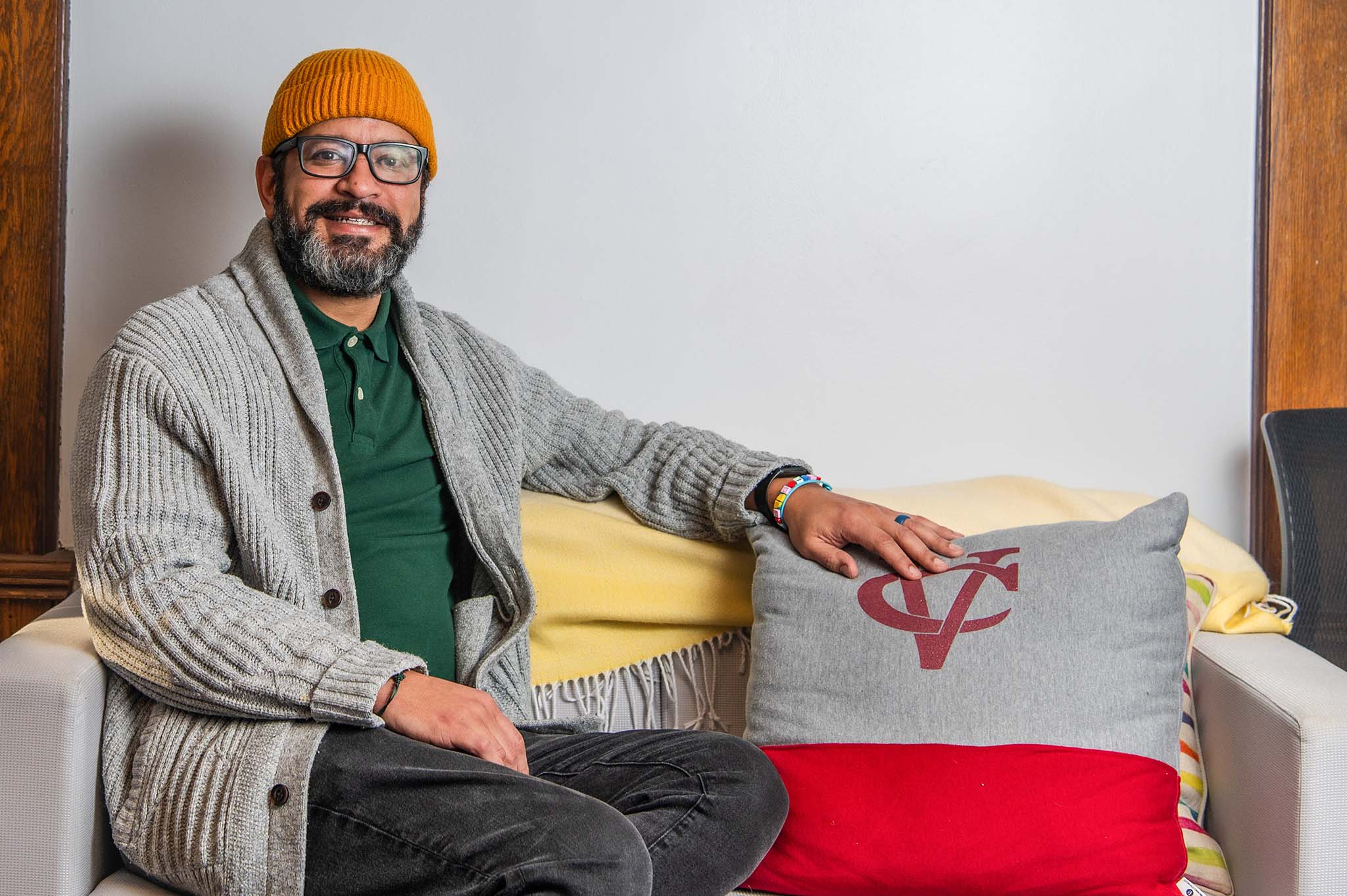 Subject sitting on a couch decorated with a Vassar logo pillow