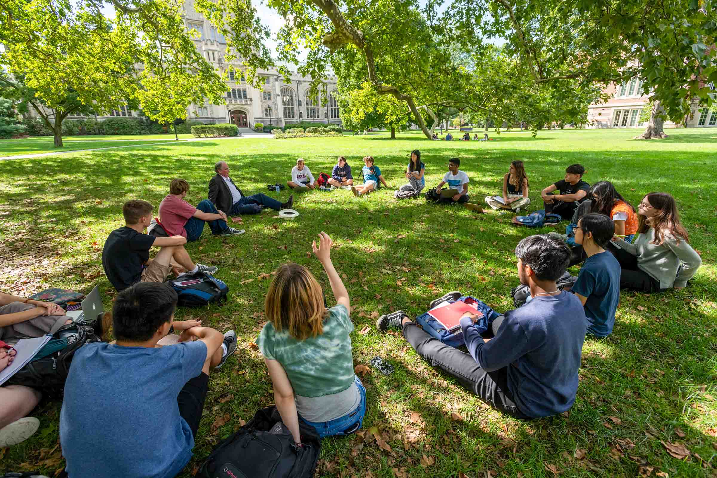 A large group of people sitting in a circle on the grass. 