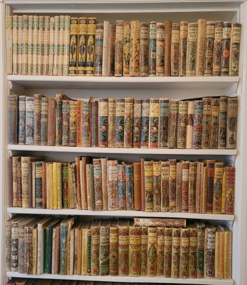 Four shelf white bookcase of Marcia McGhee Carter’s collection of Victorian Yellowbacks.