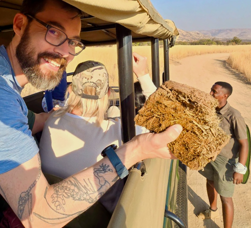 A person sitting in the back of a jeep in the desert holding a fragment of brown earth.