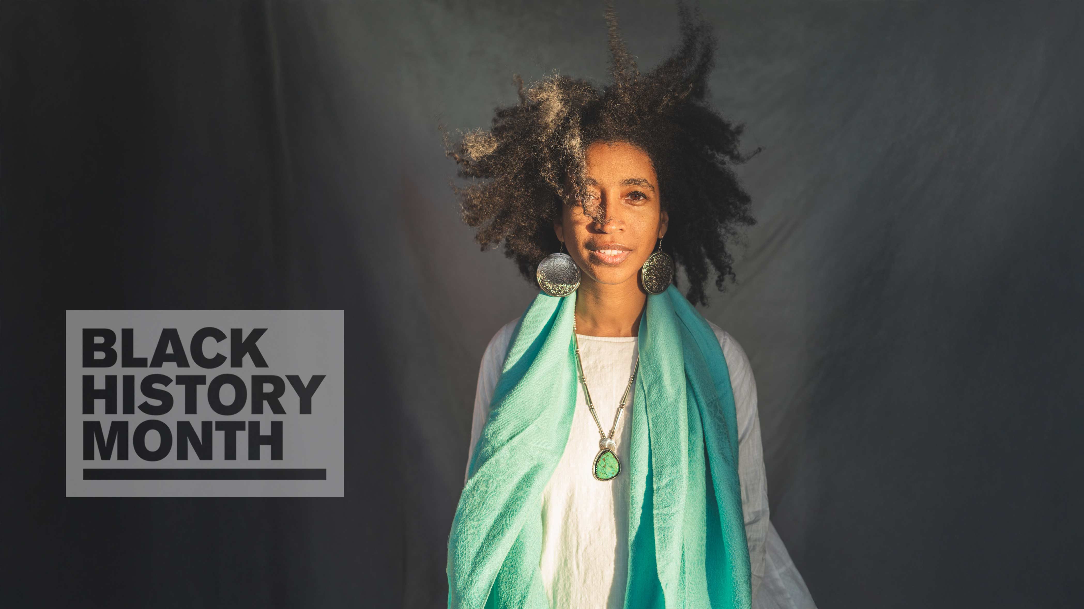 Alexis Pauline Gumb poses in front of a grey background, with a 'Black History Month' badge overlaid.