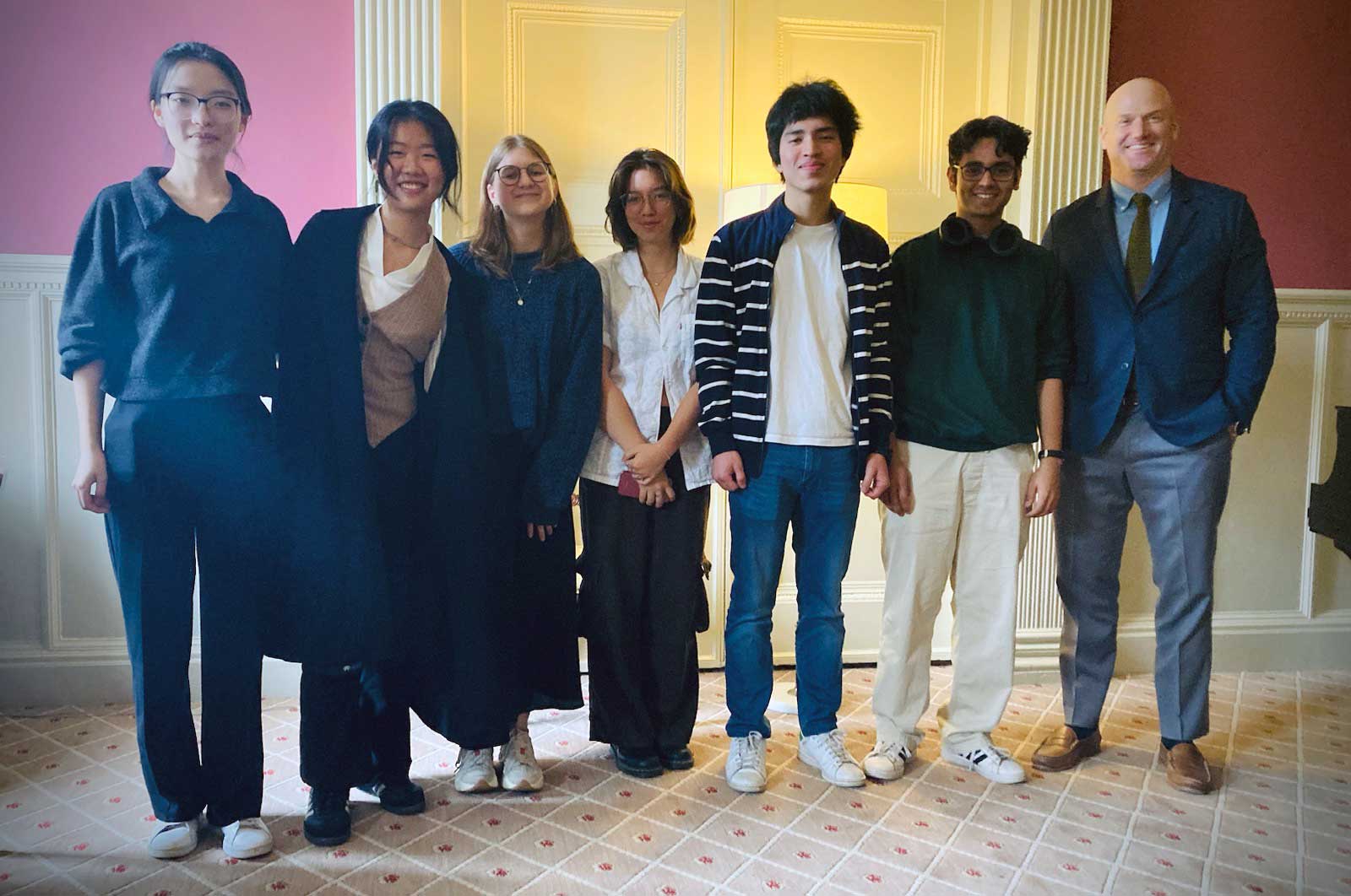 Seven people standing and smiling for a photograph indoors.