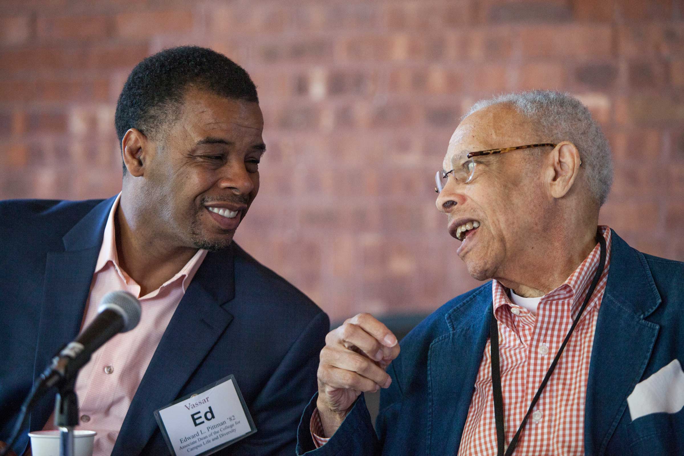 Two people sitting side by side talking and smiling.