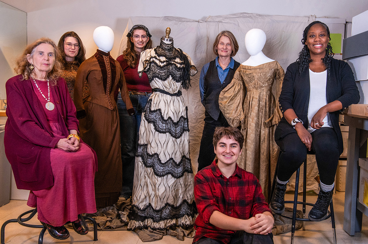 A group standing among a few mannequins adorned with dresses