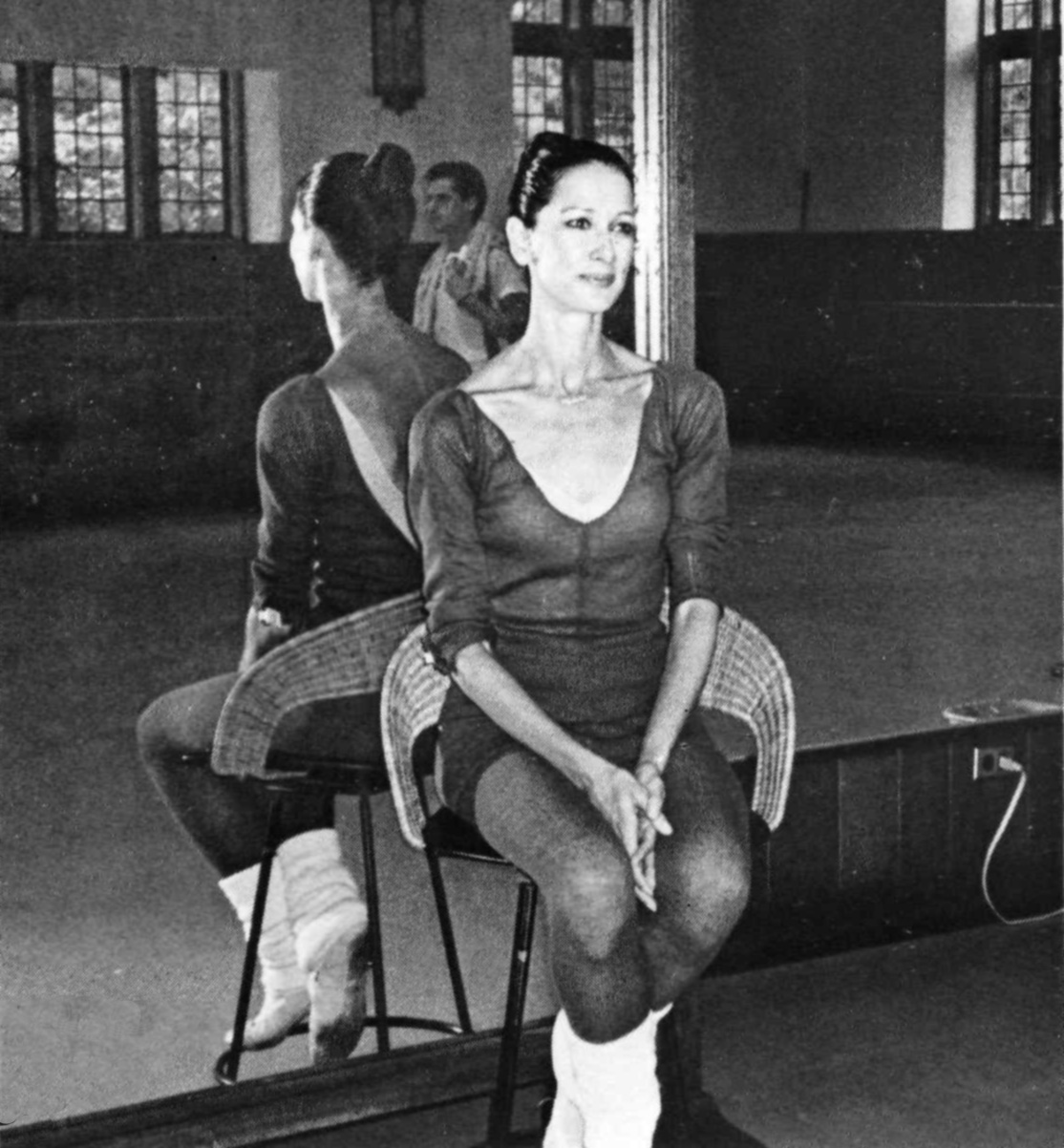 Jeanne Czula, dance teacher seated on a stool in a dance studio.