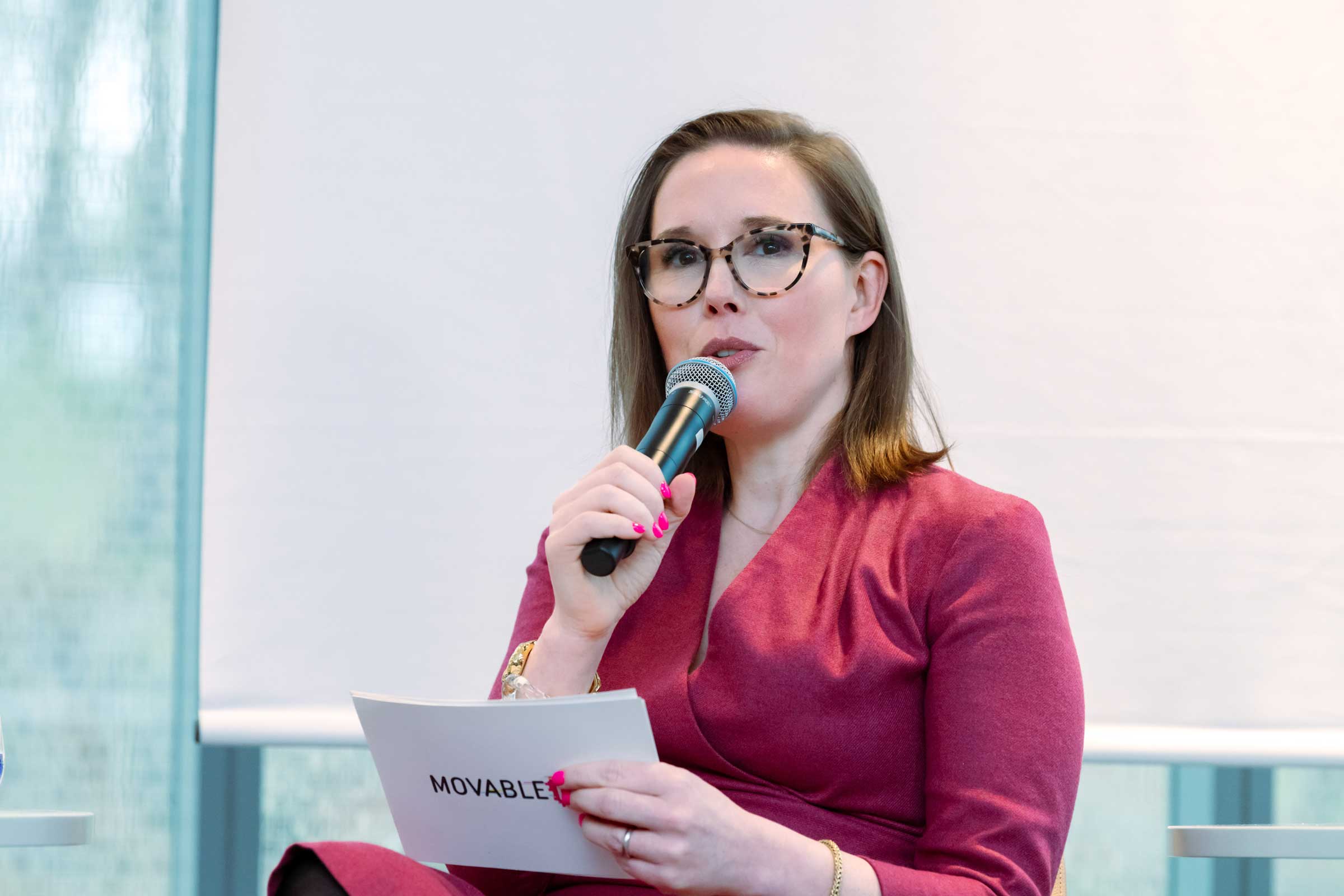 Seated person holding a microphone and speaking.