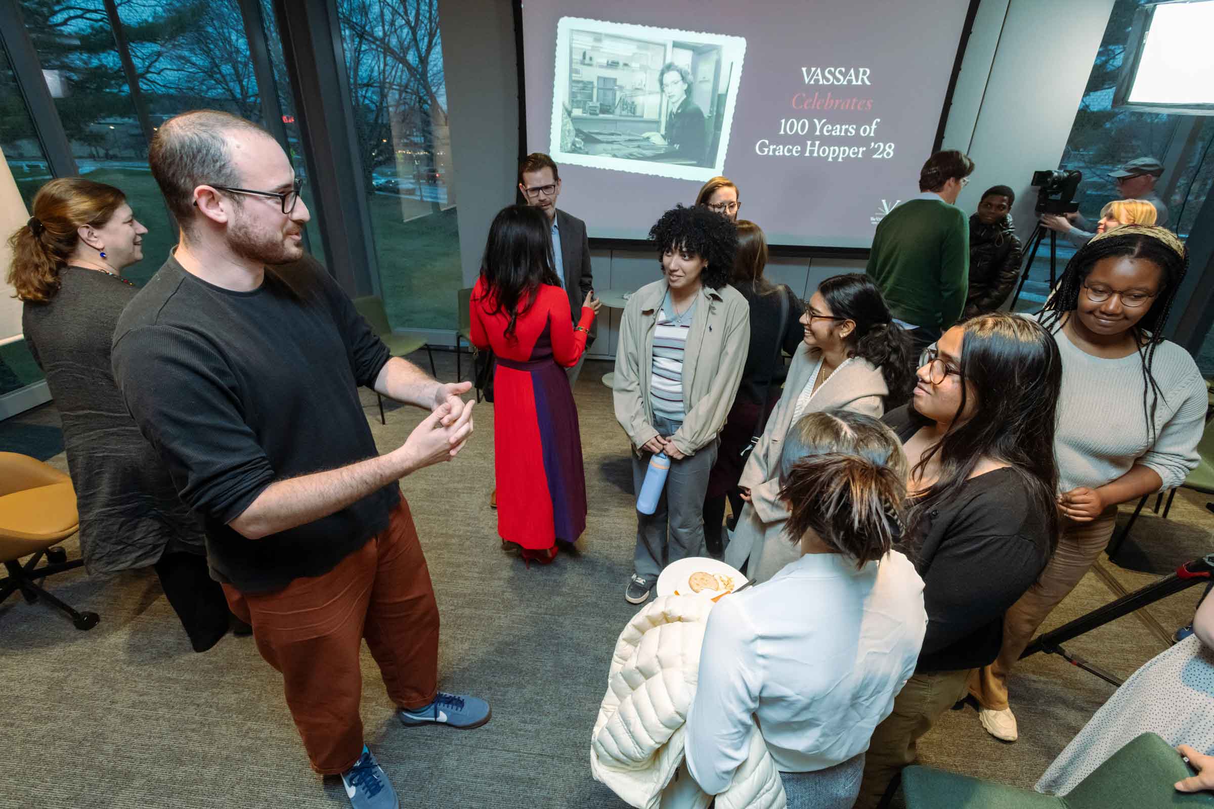 A group of people standing and listening to one person speak.