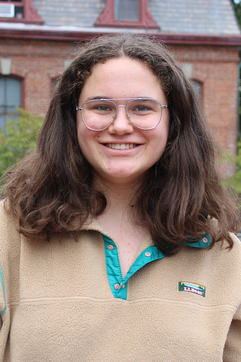 Outdoor portrait of a smiling person wearing a tan fleece with teal accents.