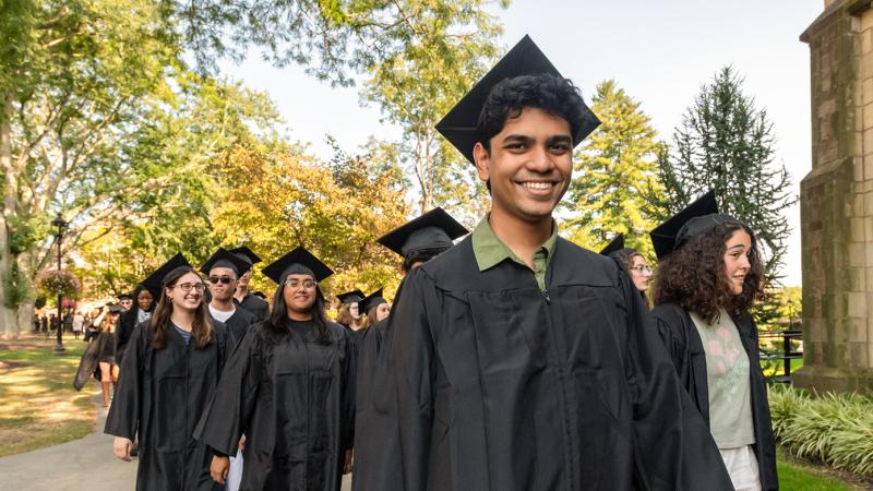 Students in grduation caps and gowns lined up outside preparing to parade into convocation.