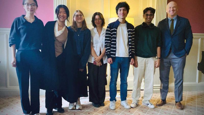 Seven people standing and smiling for a photograph indoors.