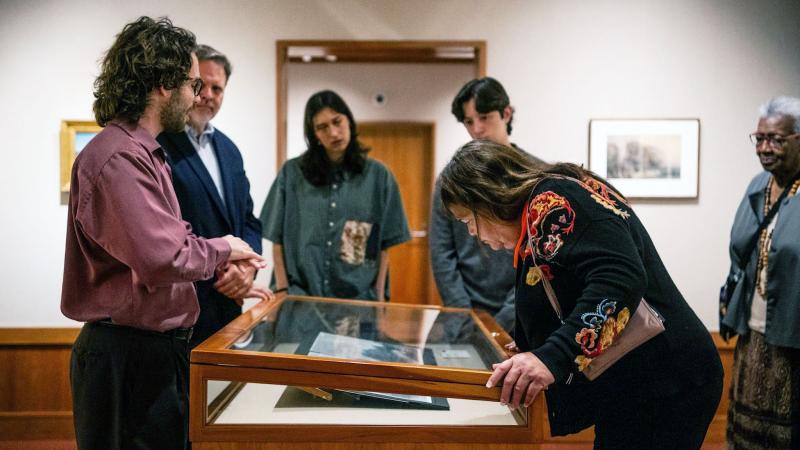 People in a museum gallery looking into a glass case.