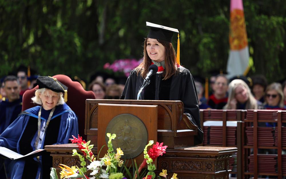 The commencement speaker in academic attire at the podium during a graduation ceremony.