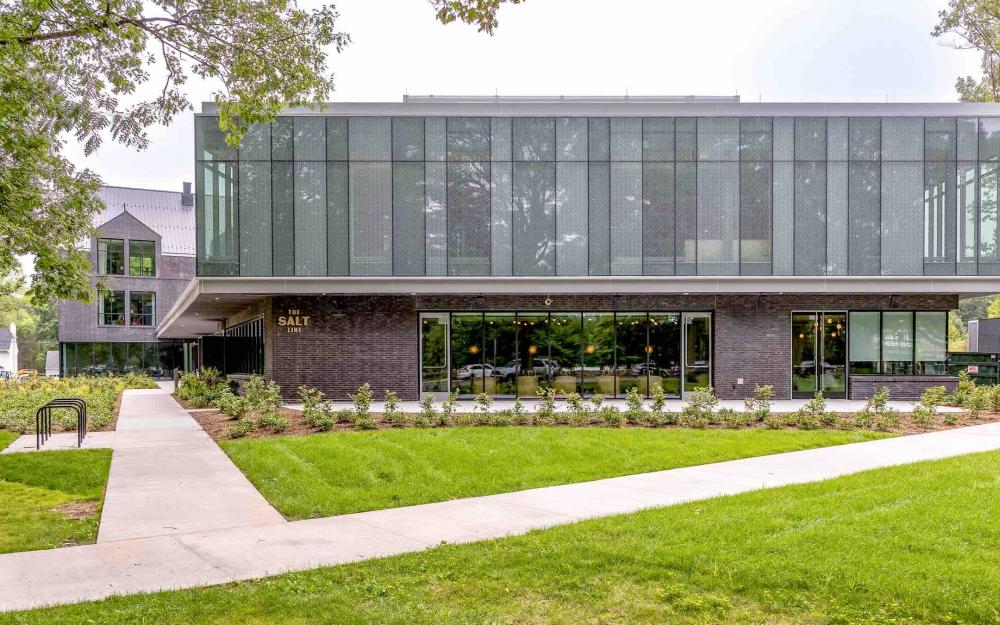 Exterior shot of a glass and metal building with large windows looking into an event space.