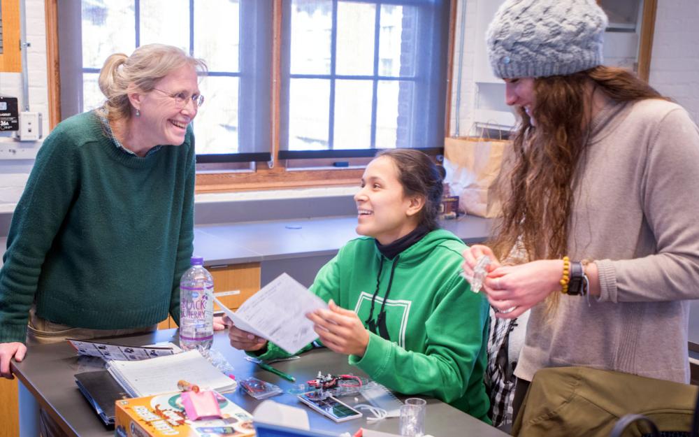 Three people in a classroom/lab smiling and talking.