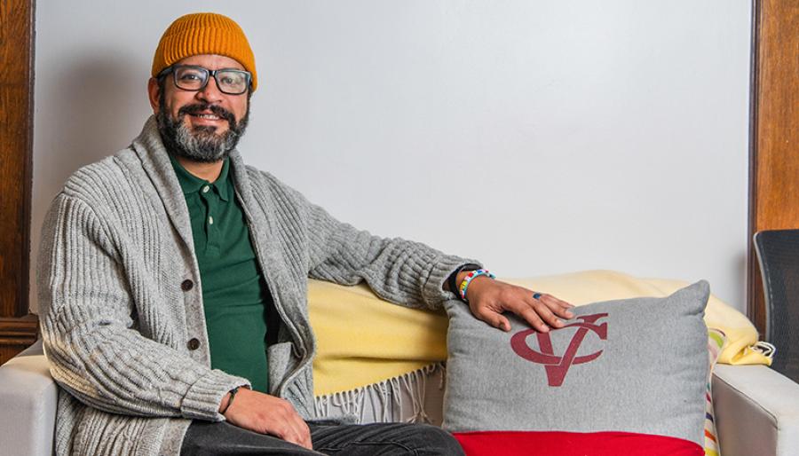 Subject sitting on a couch decorated with a Vassar logo pillow