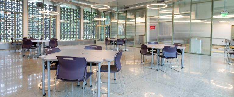 Bright room with several square tables with four chairs and circular lighting overhead