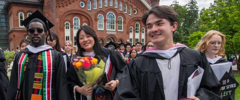 Group of people in graduation ceremony attire walking and smiling.