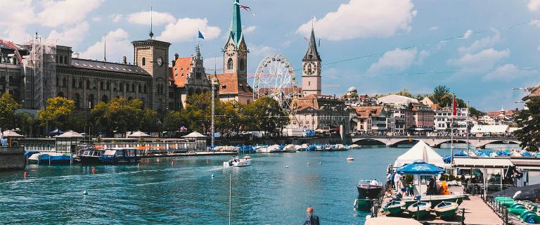 A river running through Zurich, Switzerland with boats and the city skylin.