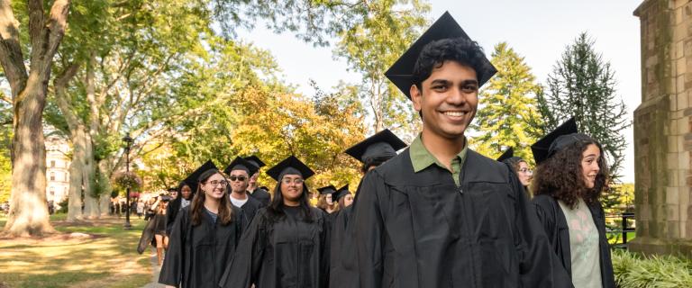 Students in grduation caps and gowns lined up outside preparing to parade into convocation.