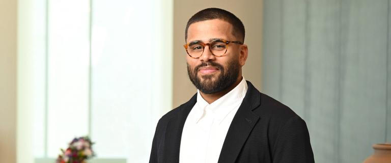 A portrait of Stephane Andrade, a person with dark hair and beard, glasses, and a black jacket.