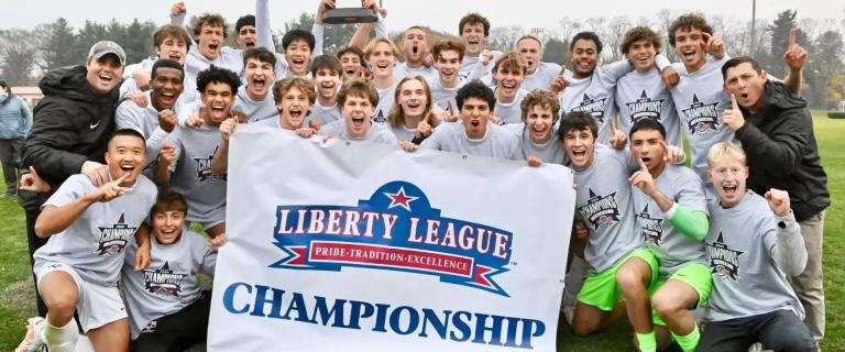 A group of people celebrating behind a banner that reads: Liberty League Championship, Pride, Tradition, Excellence.