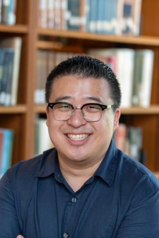 A portrait photo of Harrison Shieh in front of a bookshelf.