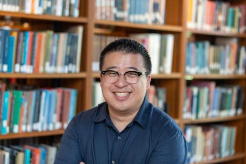 A photo of Harrison Shieh in front of a bookshelf.