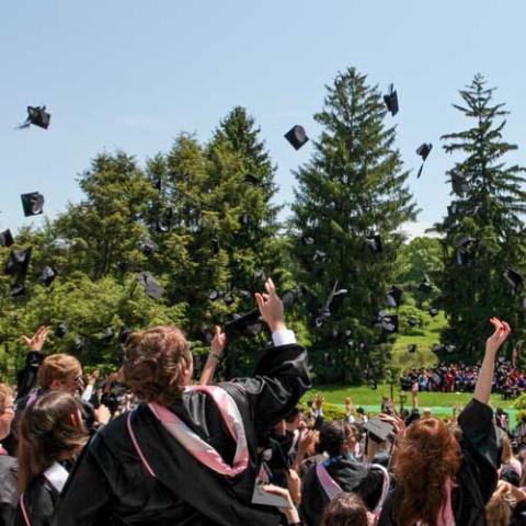 Photo: seniors throwing caps in the air at Commencement