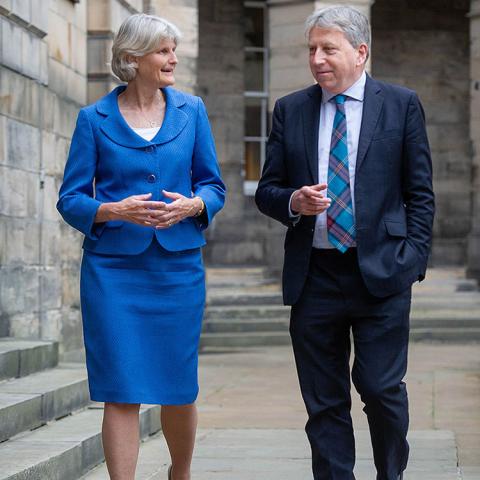 President Elizabeth H. Bradley and Peter Mathieson, Principal and Vice Chancellor of the University of Edinburgh (Scotland) walking and talking with stone buildings in the background.