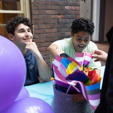 Two people sitting at a desk with with purple balloons in front of them