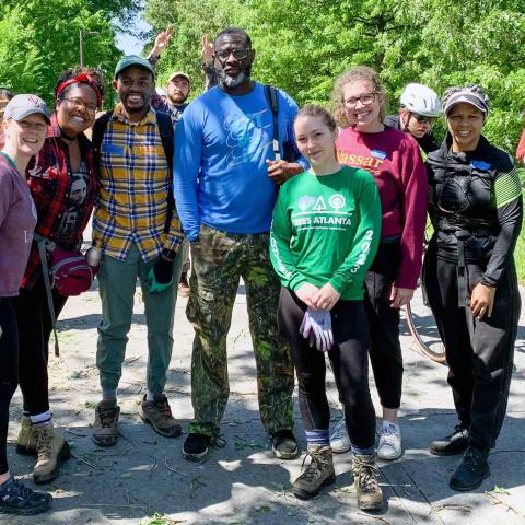 A group of people standing together on a paved road in a wooded area