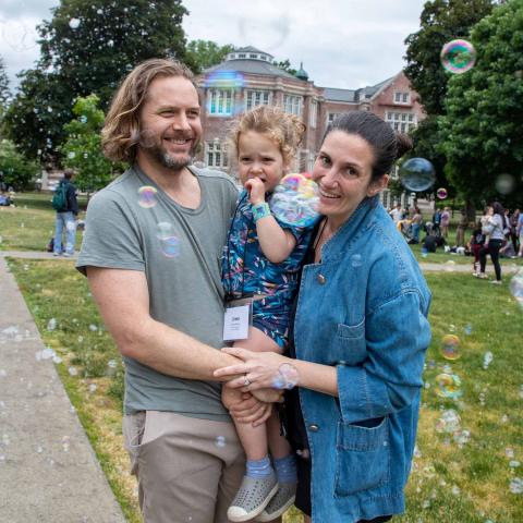 Man and woman holding a girl surrounded by bubbles