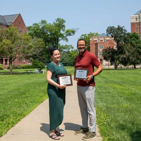 Yetty Marquez-Santana, Vassar’s Director of Residential Education, and Luis Inoa, Associate Dean of the College for Residential Life and Wellness, pose on Vassar quad with awards from the Association of College and University and Housing.