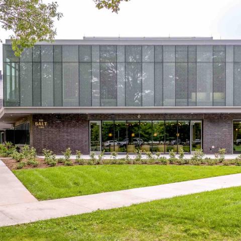 Exterior shot of a glass and metal building with large windows looking into an event space.