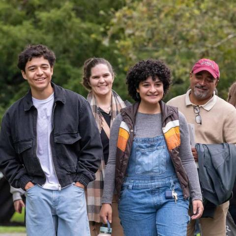 Group of smiling people walking outdoors and taking in fall foliage.