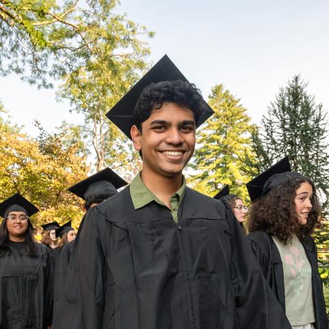 Students in grduation caps and gowns lined up outside preparing to parade into convocation.