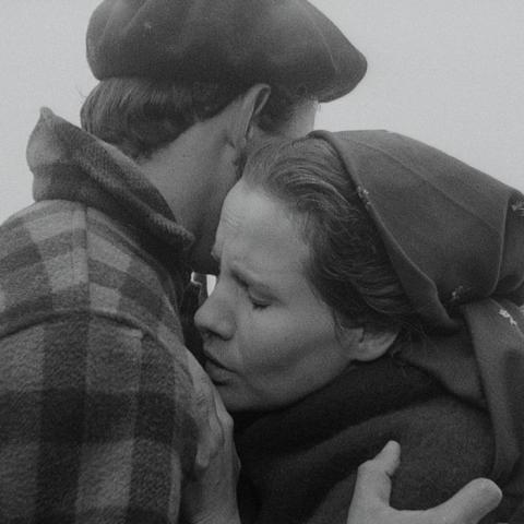 Black and white image of two people dressed for warmth in a gentle hug.