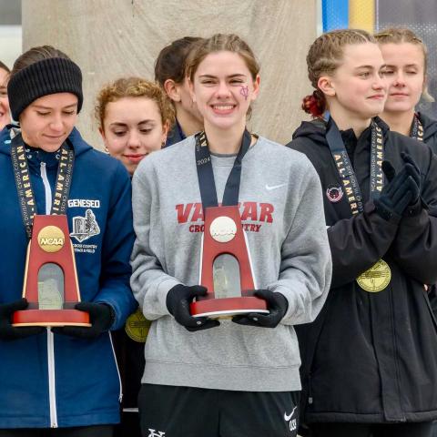 Group of athletes in winter wear holding trophies.