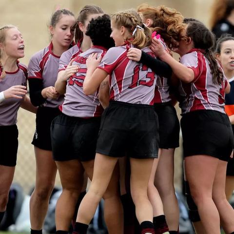 A group of rugby players hugging and celebrating.