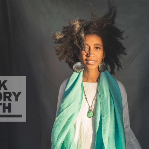 Alexis Pauline Gumb poses in front of a grey background, with a 'Black History Month' badge overlaid.