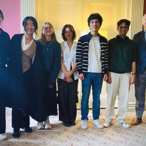 Seven people standing and smiling for a photograph indoors.