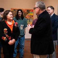 People standing in an art gallery smiling and talking.